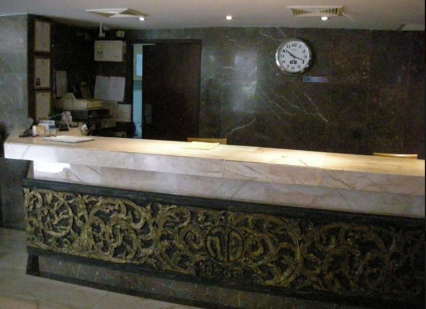 Suriwongse Hotel Bangkok reception desk with ornate carved front and wall clock