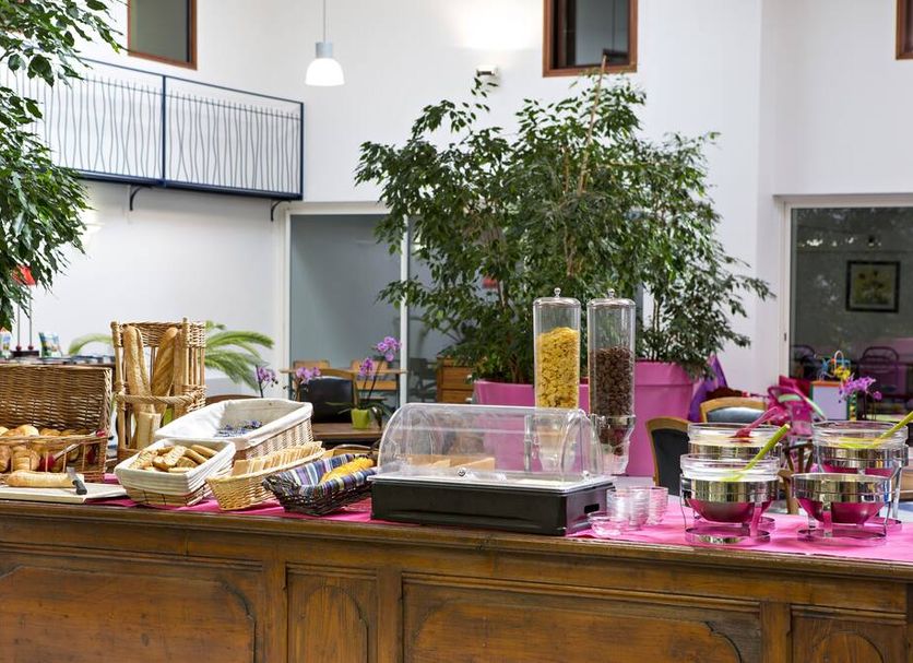 B&B HOTEL Aurillac Le Lioran breakfast buffet with pastries, fruit, and cereal in a bright atrium