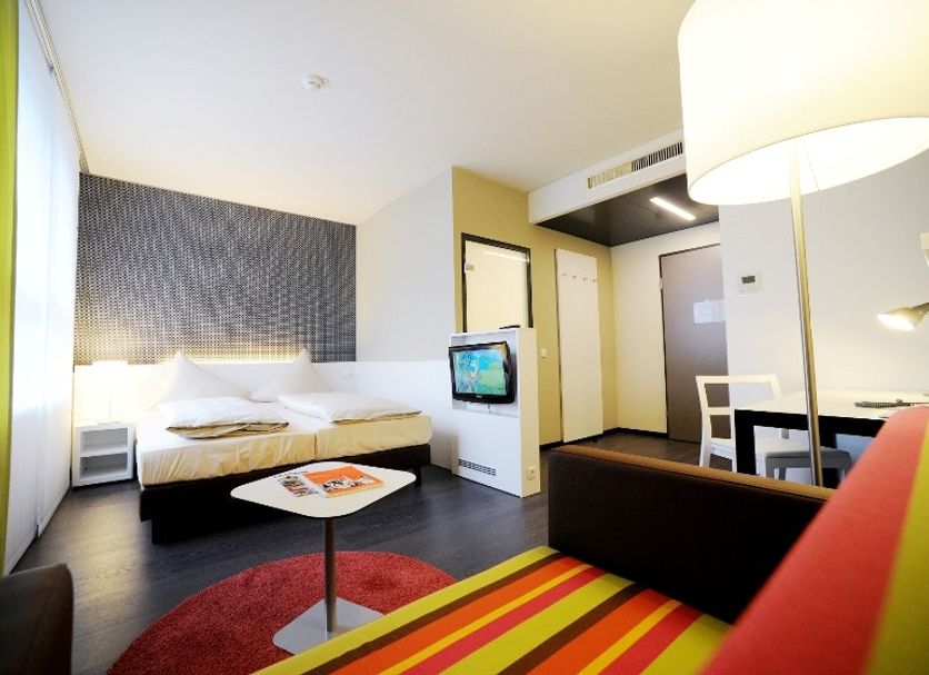 harry's home Dornbirn hotel & apartments guest room with bed, sofa, desk and seating area