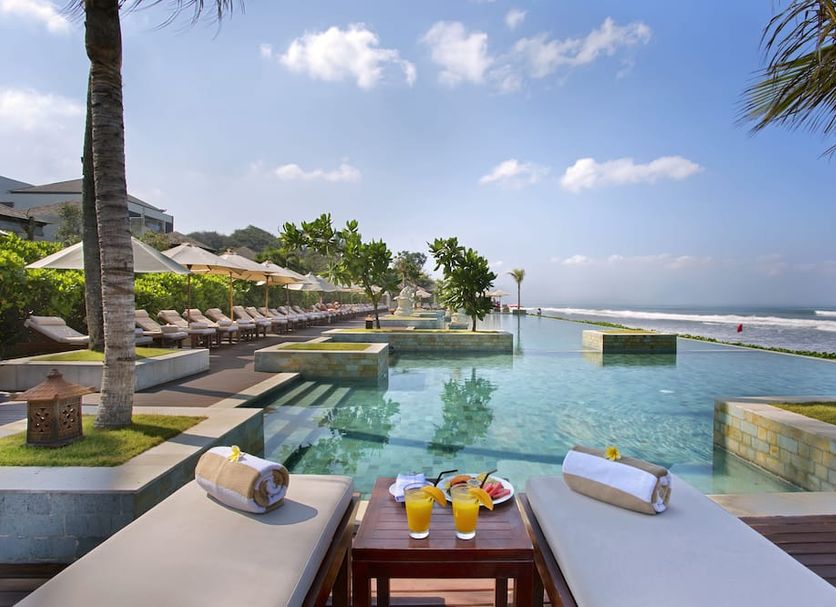 The Seminyak Beach Resort & Spa in Kuta: oceanfront infinity pool with loungers and drinks