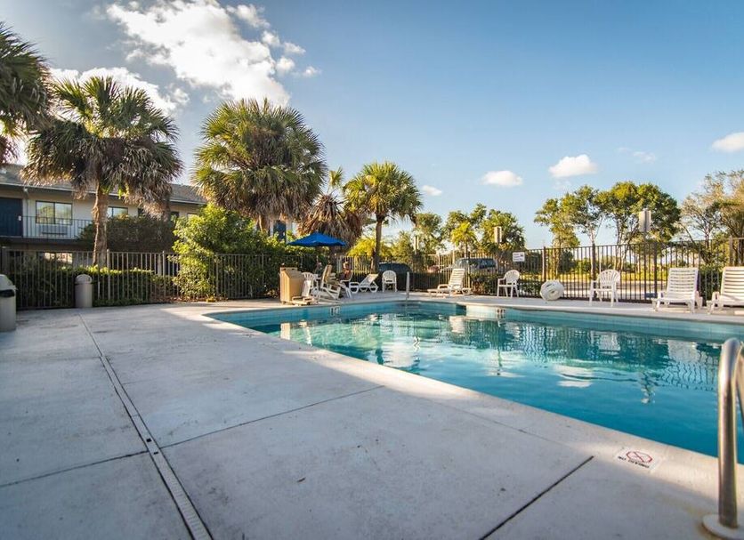 Motel 6 Ft Pierce pool area with palm trees and lounge chairs in Fort Pierce