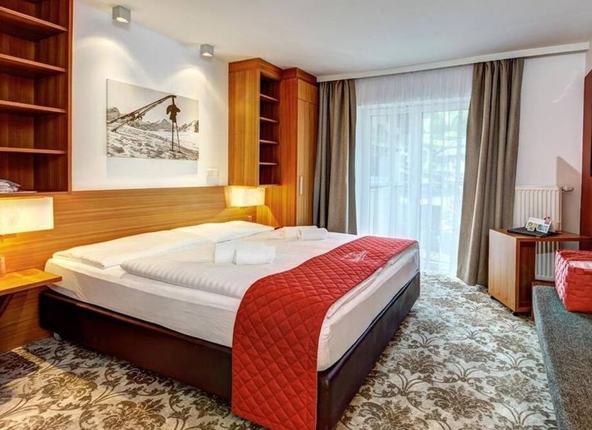 Alpenparks Hotel Maria Alm bedroom with double bed, wood accents and balcony door in Maria Alm am Steinernen Meer