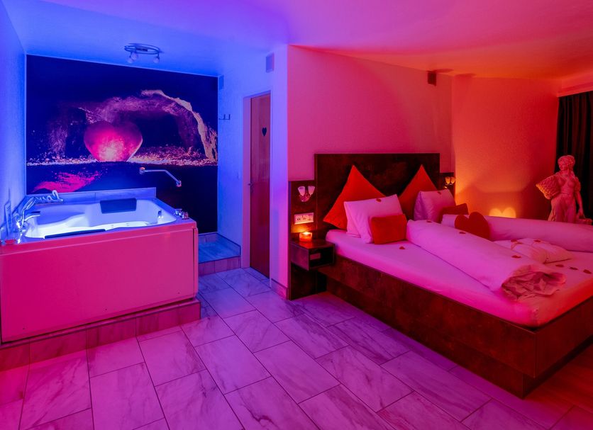 dala Hotel & Apartments in Leukerbad: neon-lit room with bed, Jacuzzi tub, and colorful wall art