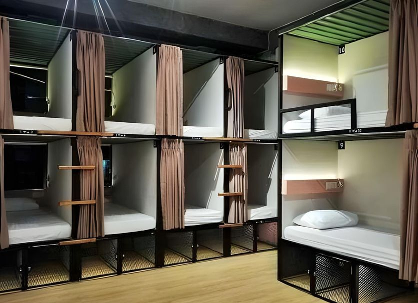 Pinx's Hostel Jakarta dorm room with stacked bunk beds, privacy curtains, and wood flooring