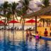 Musket Cove Island Resort and Marina in Malolo Island, beachfront pool with red umbrellas and palm trees at sunset