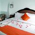 Blooming Paradise Thekkady room with king bed, orange accents, flower petals, and seating area