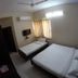 Sr Residency, Tiruchirappalli room with two single beds, wall-mounted TV and window curtains