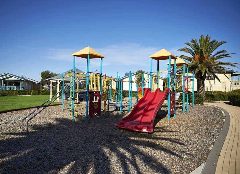 The Retreat at West Beach Parks in West Beach: colorful playground with slides and palm tree