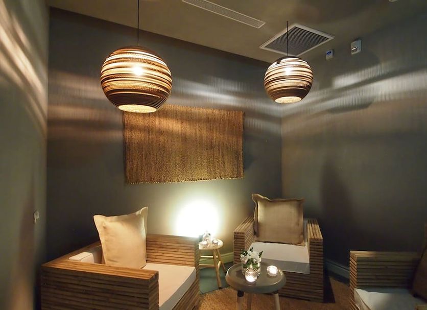 Carmella Boutique Hotel Haifa lounge seating area with woven chairs and hanging globe pendant lights
