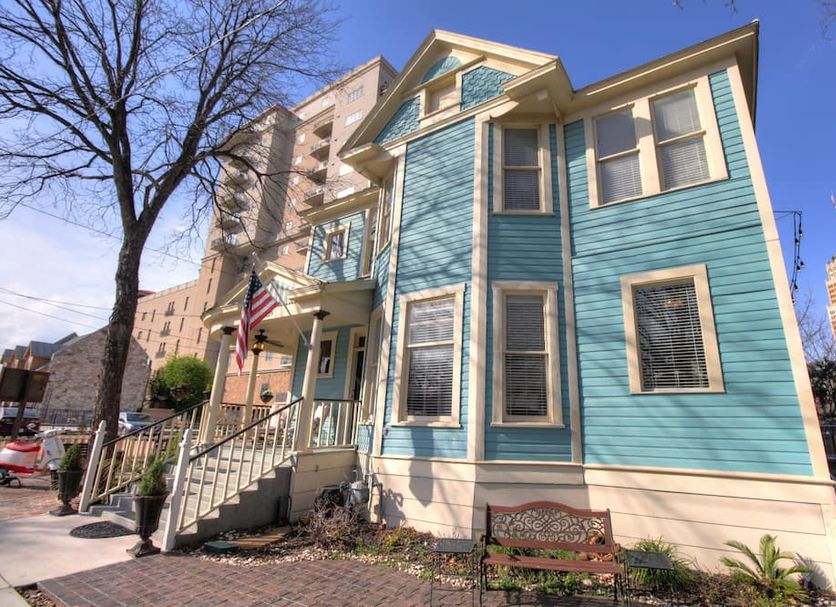 Inn on the Riverwalk in San Antonio, blue Victorian-style hotel exterior with porch and stairs