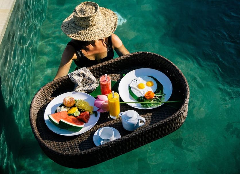 Suarapura Resort & Spa in Tegalalang: woman enjoying breakfast on a floating tray in a turquoise pool