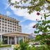 Haiqing Hotel Qingdao exterior with grand entrance, balconies and landscaped garden under blue sky