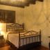 Las Iglesias Antigua guest room with iron bed, wooden beams, dresser and mirror