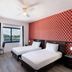 Notebook Miami Beach room with two twin beds, window view, and red patterned accent wall
