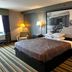 Super 8 by Wyndham Mound City guest room with king bed, chair, bedside lamps and striped carpet