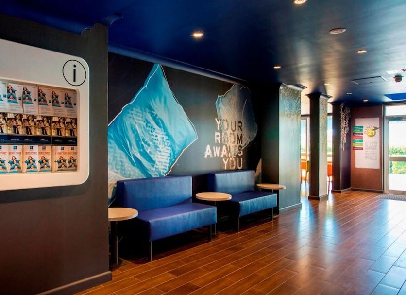 Lobby seating area at ibis budget Dandenong with blue benches, mural wall art, and wood flooring