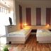 Gästehaus Seewarte in Flensburg room with two single beds, wood flooring, and a black armchair
