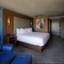 Bally's Baton Rouge Hotel guest room with king bed, blue chair, and modern brick accent wall