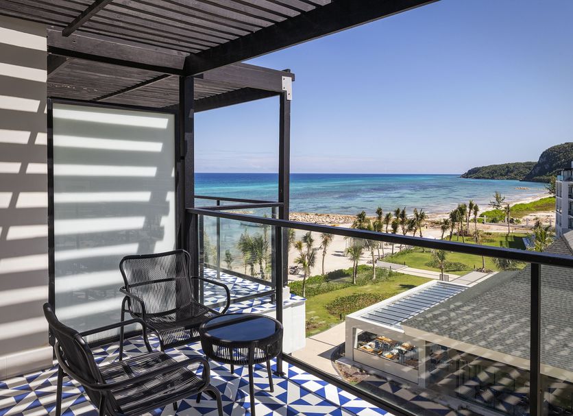 Ocean Eden Bay balcony with seating and glass railing overlooking a beach, pool, and ocean in Duncans