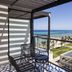 Ocean Eden Bay balcony with seating and glass railing overlooking a beach, pool, and ocean in Duncans