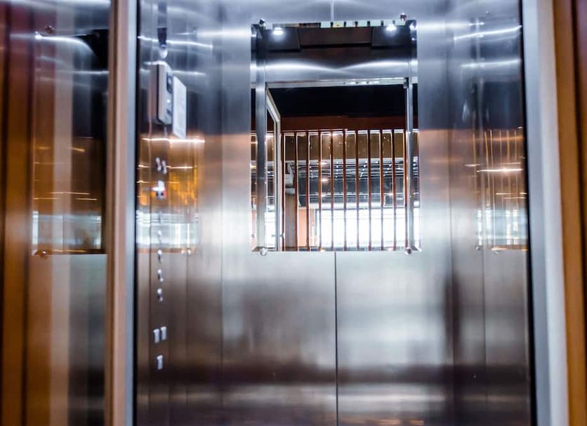 GN Luxury Hostel Bangkok elevator interior with stainless steel walls and mirrored panels
