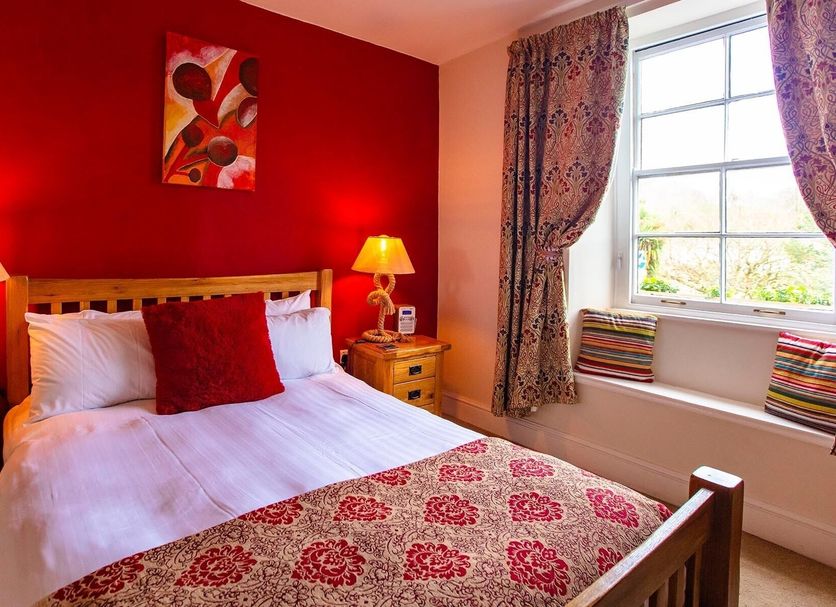 The Ship In Dock Inn in Dartmouth bedroom with red walls, double bed, bedside lamps and window seat