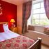 The Ship In Dock Inn in Dartmouth bedroom with red walls, double bed, bedside lamps and window seat
