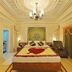 Hotel Ambica Empire Chennai ornate suite with king bed, chandelier, mural wall art and draped windows