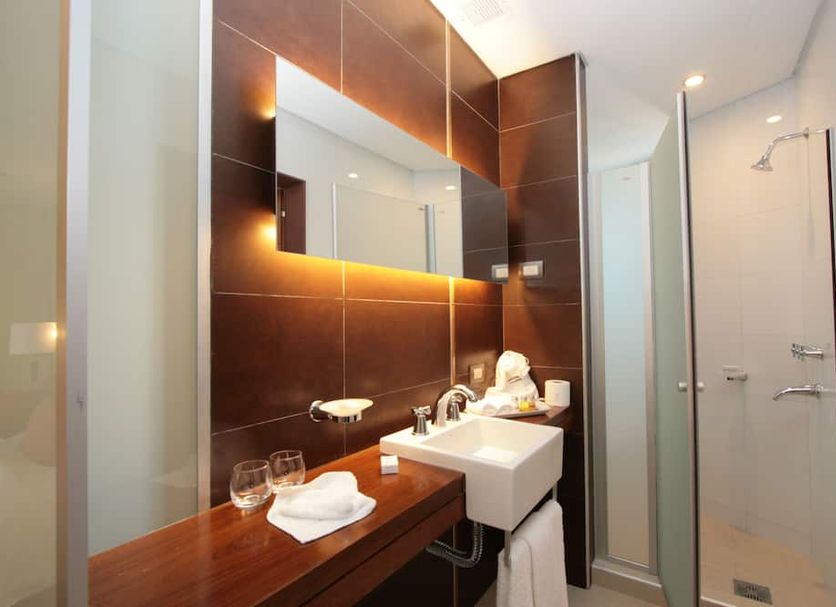 Del Bono Park Spa & Casino bathroom in San Juan with double sink, shower and glass-enclosed wet room