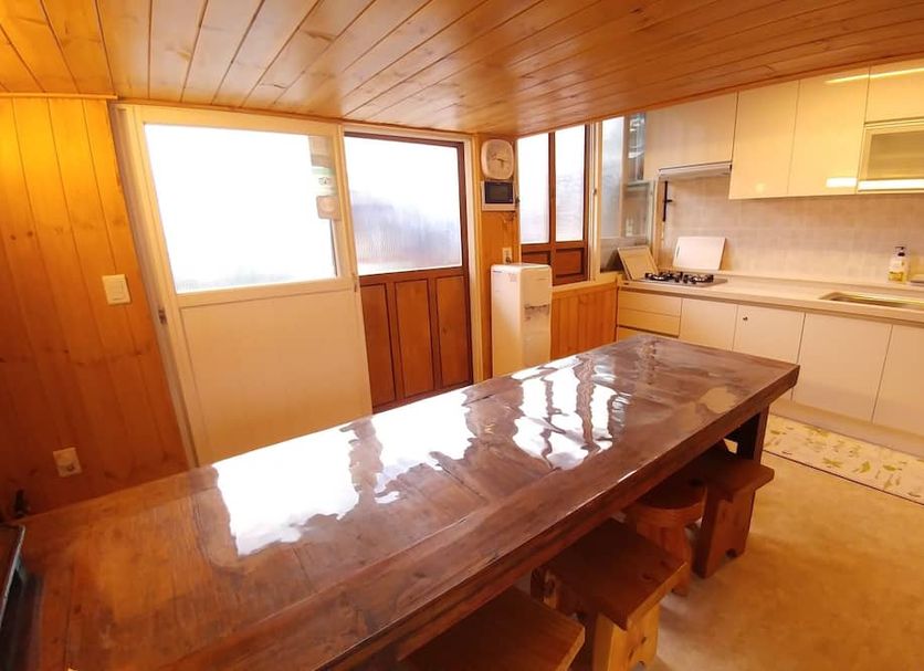 Sohyundang Guesthouse in Seoul kitchen with wooden table, cabinets, and bright windows