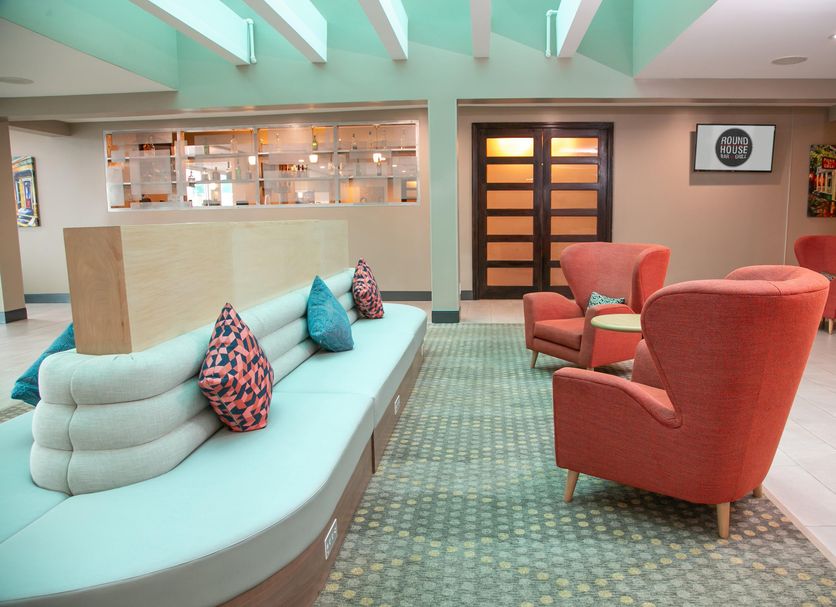 Holiday Inn Metairie New Orleans lobby with curved seating area and coral lounge chairs