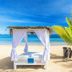 Voi Amarina Resort in Nosy Be: beach cabana with sheer curtains beside a palm tree and turquoise sea.