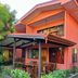 Hotel Los Ranchos in Jacó: coral two-story guesthouse with covered patio and tropical garden