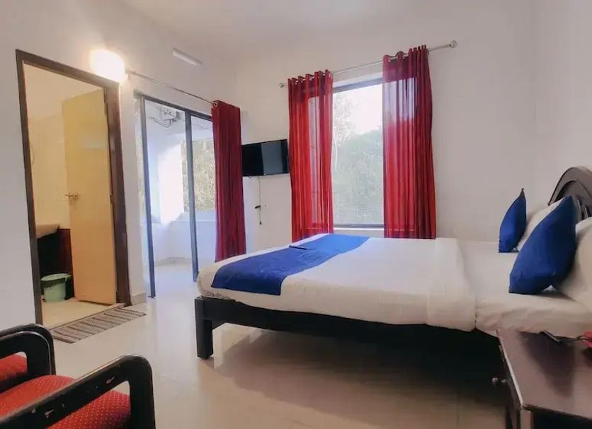 Karthika Residency in Munnar guest room with king bed, red curtains, balcony door and mountain view