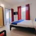 Karthika Residency in Munnar guest room with king bed, red curtains, balcony door and mountain view