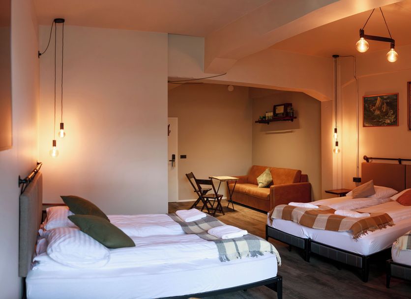 Kex Reykjavík in Reykjavik: hotel room with multiple beds, seating area, and warm pendant lighting