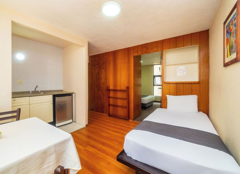 Capital O Hotel Suites Marne, Mexico City room with twin beds, kitchenette and wood-paneled walls