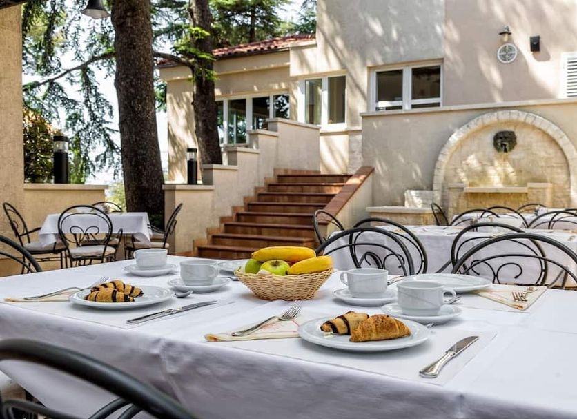Hotel Abalone in Crikvenica outdoor breakfast terrace with set tables, croissants, and stone fountain