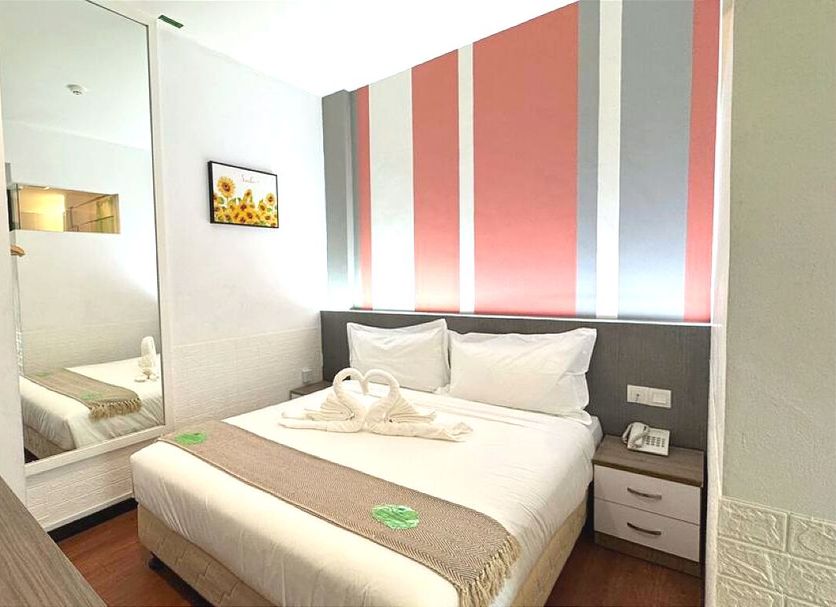 Yan Hotel in George Town guest room with double bed, wall mirror, TV and striped accent wall