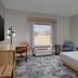 Hampton Inn Crossville guest room with king bed, desk, chair, window view and armchair