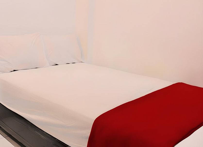 Infinite Residence Bandung guest room with a neatly made bed and red throw blanket