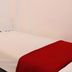 Infinite Residence Bandung guest room with a neatly made bed and red throw blanket