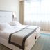 Golden Tulip Aix Les Bains guest room with king bed, wall lamps, and large window in Aix-les-Bains