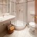 Family & Sporthotel Kärntnerhof bathroom with curved glass shower, sink, toilet and tiled walls in Bad Kleinkirchheim