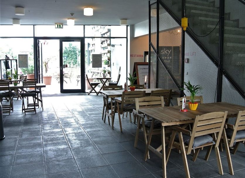 Chillten Bottrop lobby seating area with wooden tables, chairs, and glass entrance in Bottrop