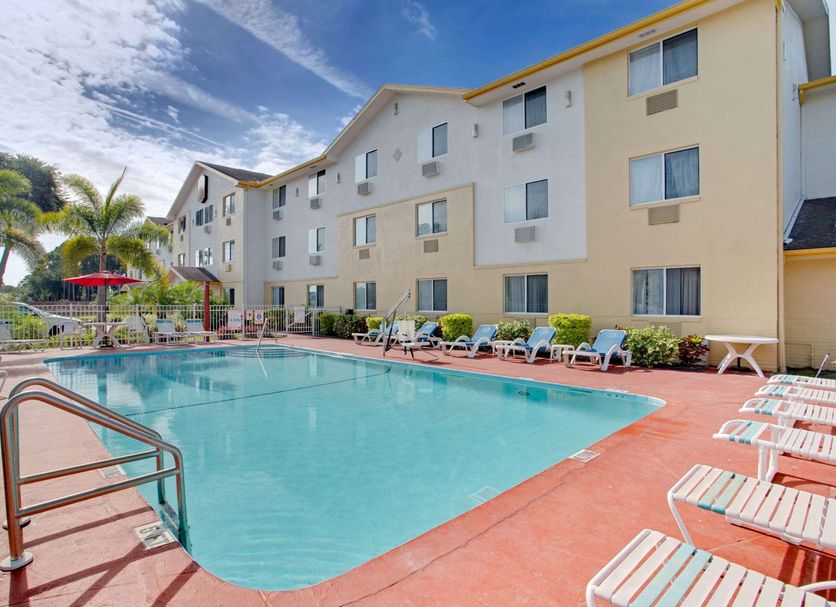 Super 8 by Wyndham Clearwater/St. Petersburg Airport pool with lounge chairs and palm trees in Clearwater