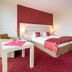 Aspire AcarA Oldenburg guest room with double bed, seating area and red carpet