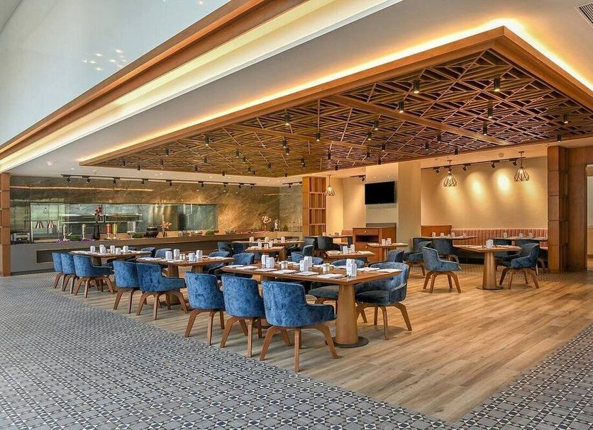 Welcomhotel By Itc Hotels, Ashram Road, Ahmedabad dining area with blue chairs and wood ceiling