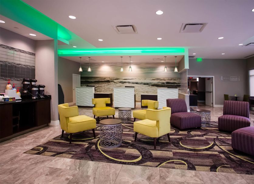 La Quinta Inn & Suites by Wyndham Virginia Beach lobby with yellow chairs, purple seating and modern lighting