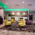 La Quinta Inn & Suites by Wyndham Virginia Beach lobby with yellow chairs, purple seating and modern lighting